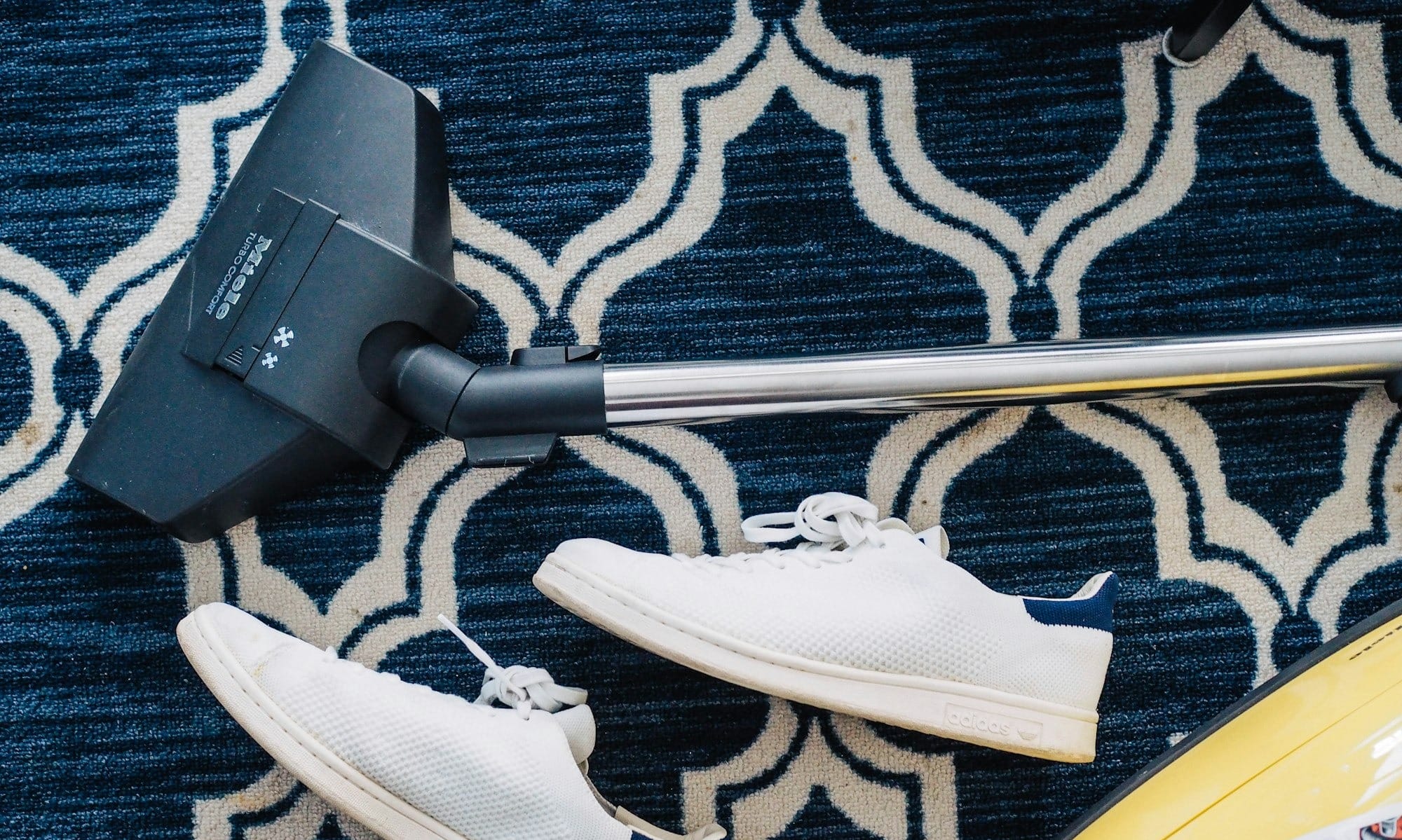 pair of white sneakers beside vacuum cleaner