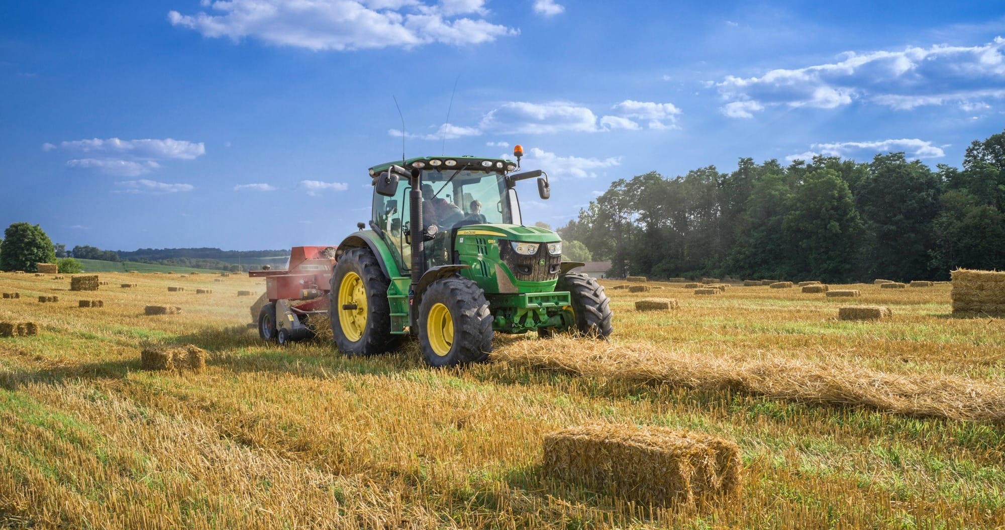 green tractor on brown grass field under blue sky during daytime