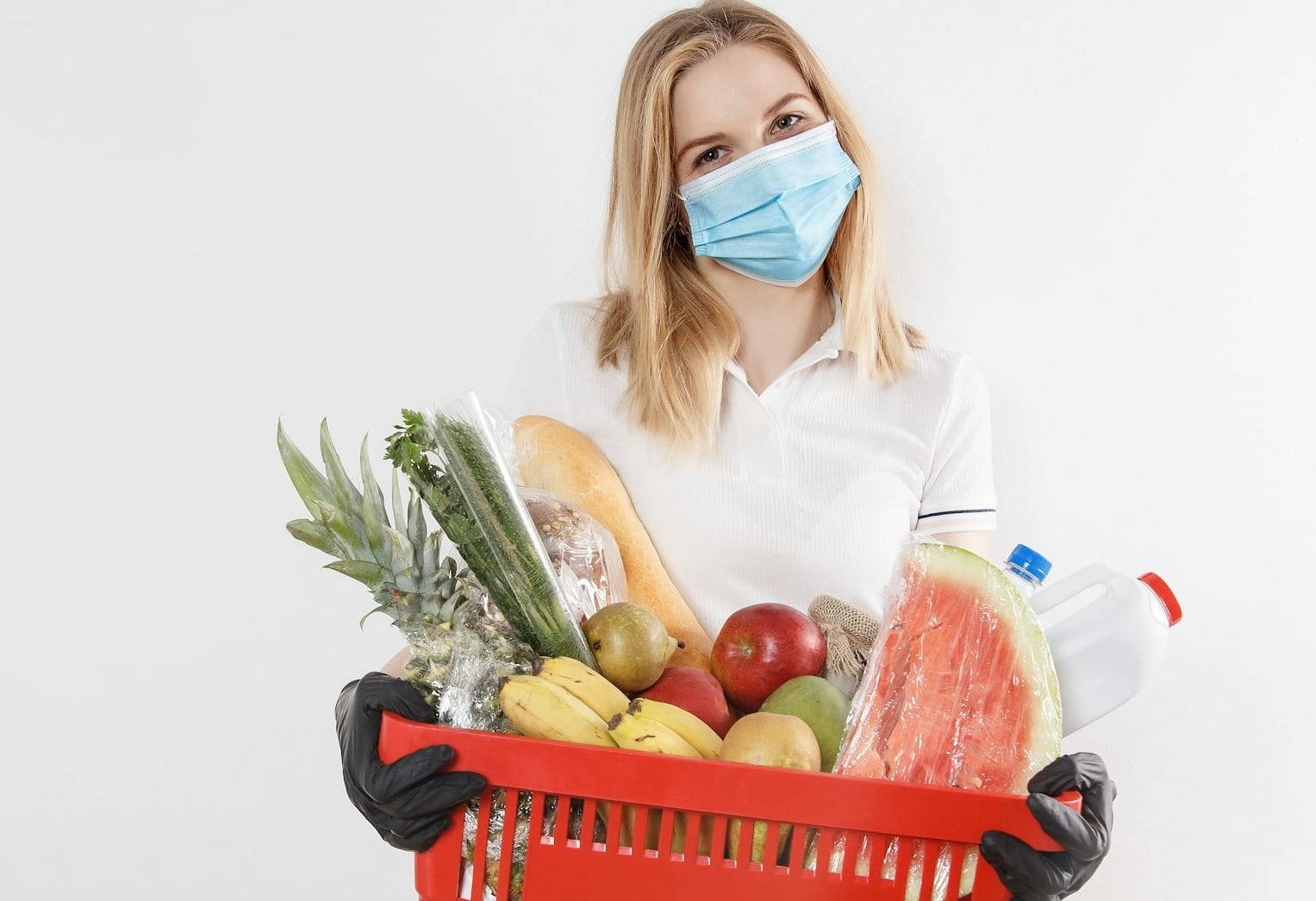 woman in white long sleeve shirt holding red plastic basket with fruits