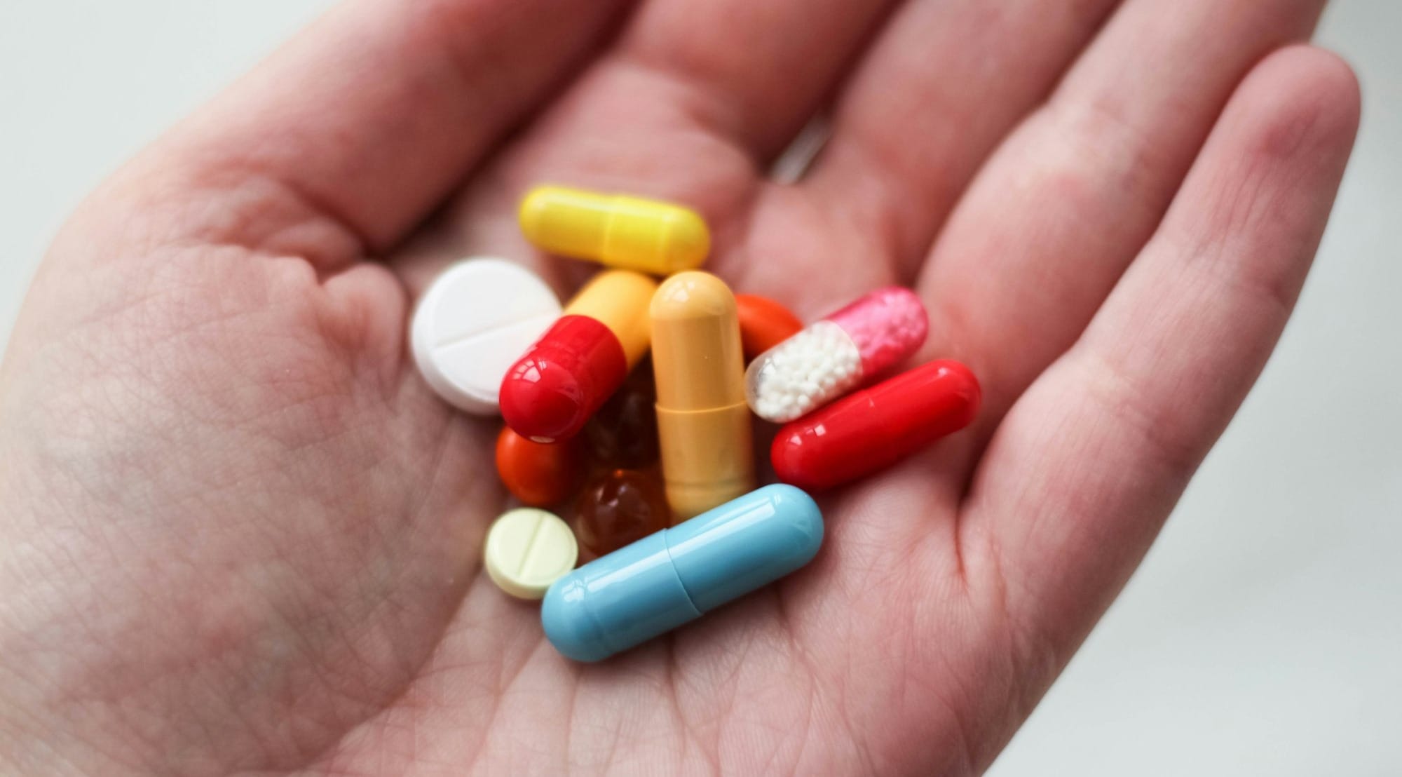 orange and white medication pill on persons hand