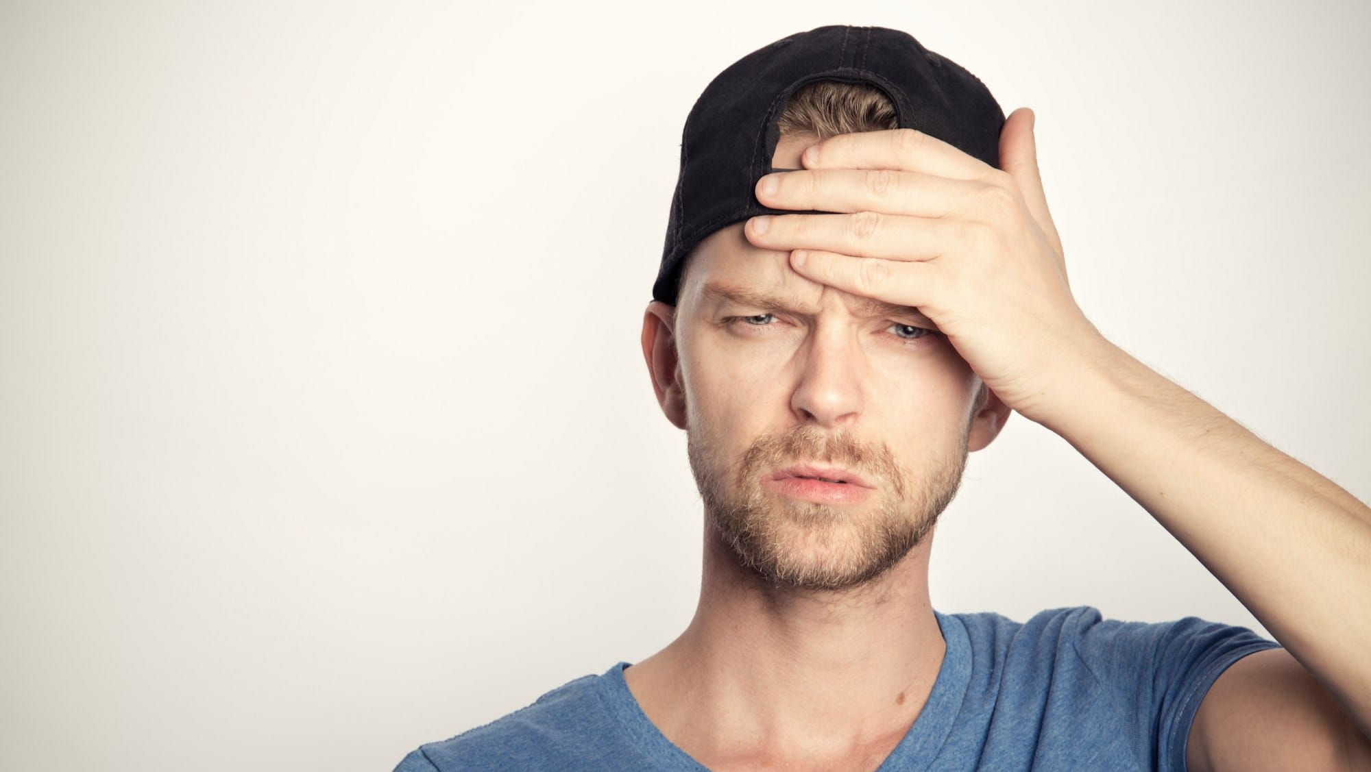 man in blue crew neck shirt covering his face